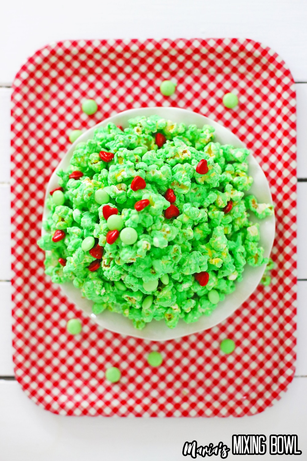 white plate on a red and white kitchen towel filled with grinch popcorn