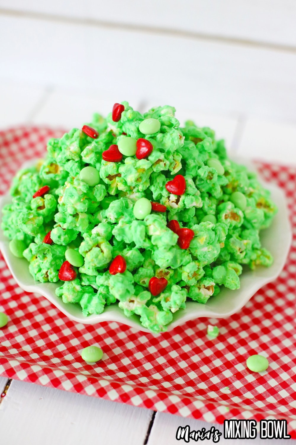 white plate on a red and white kitchen towel filled with grinch popcorn