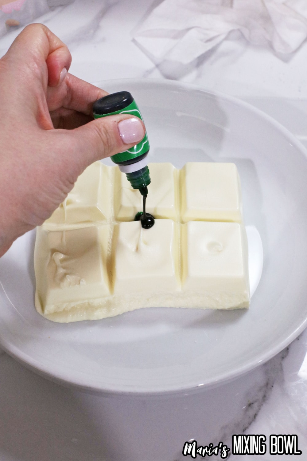 almond bark being melted with green food coloring gel being added to it