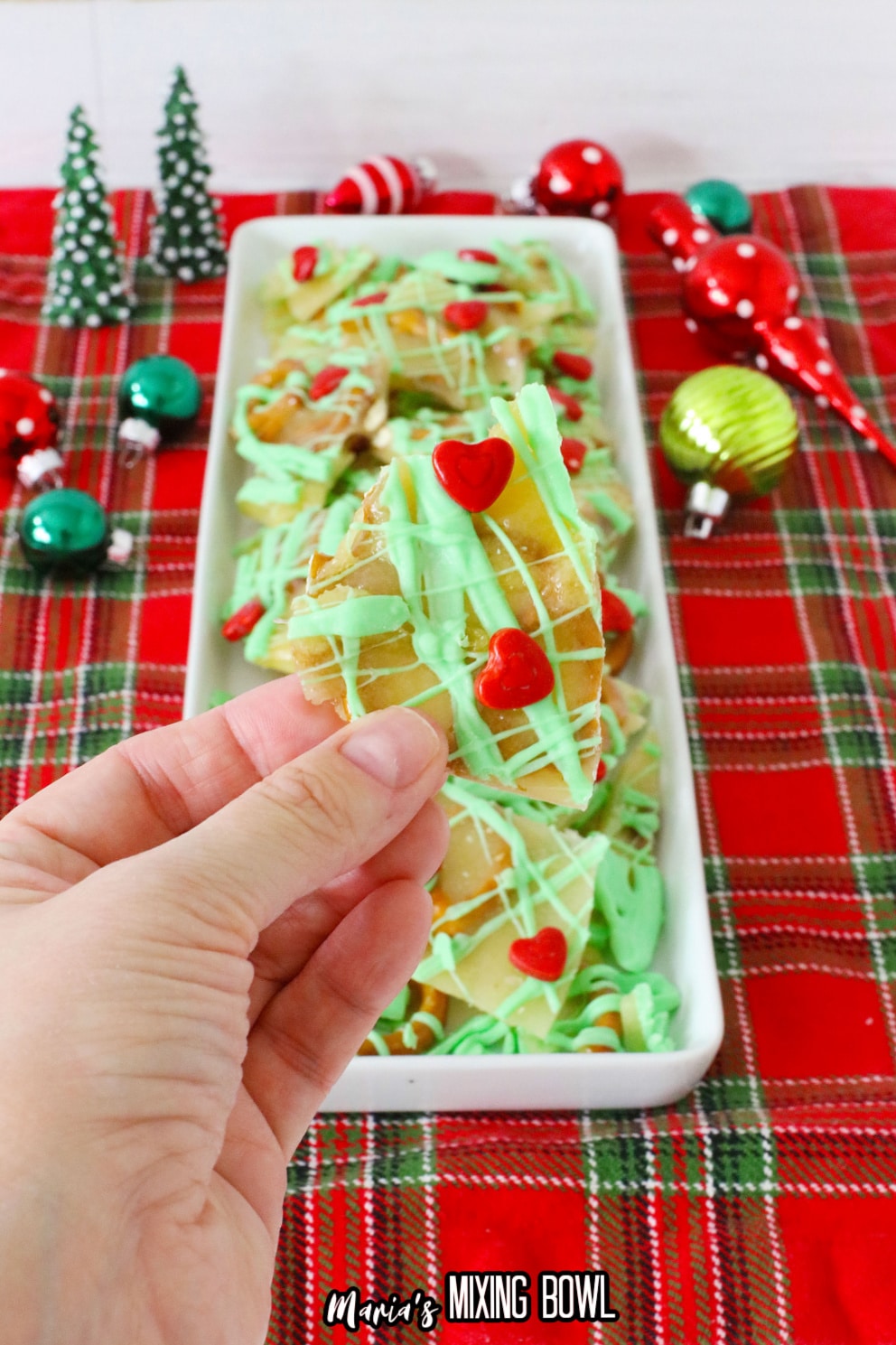 piece of grinch pretzel brittle held in a womens fingers