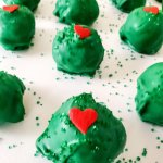 grinch truffles on a parchment lined baking sheets with the name in text for pinterest