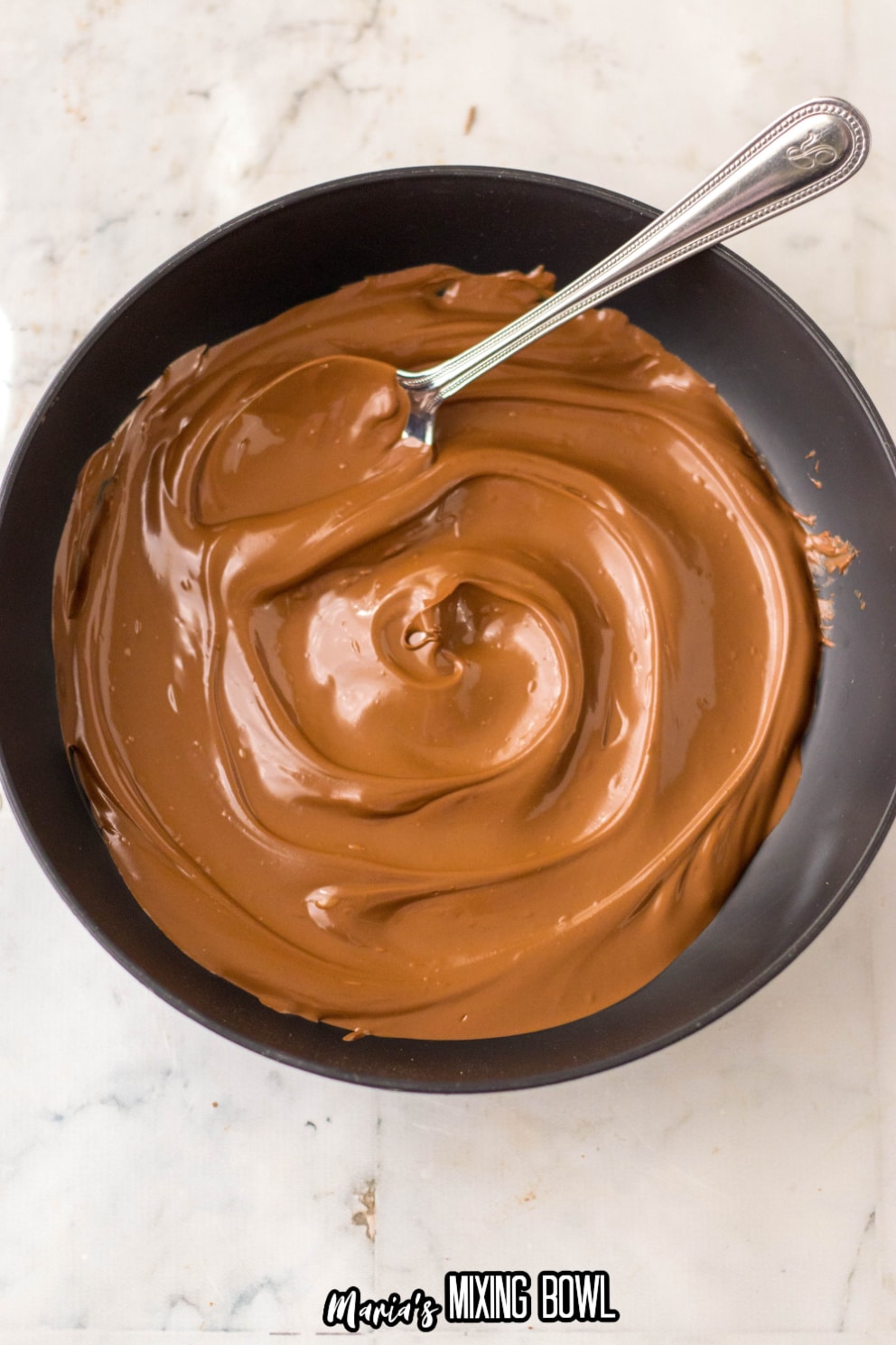 melted chocolate in a mixing bowl with a spoon