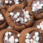 stack of hot cocoa thumbprint cookies on a white plate with the name in text for pinterest