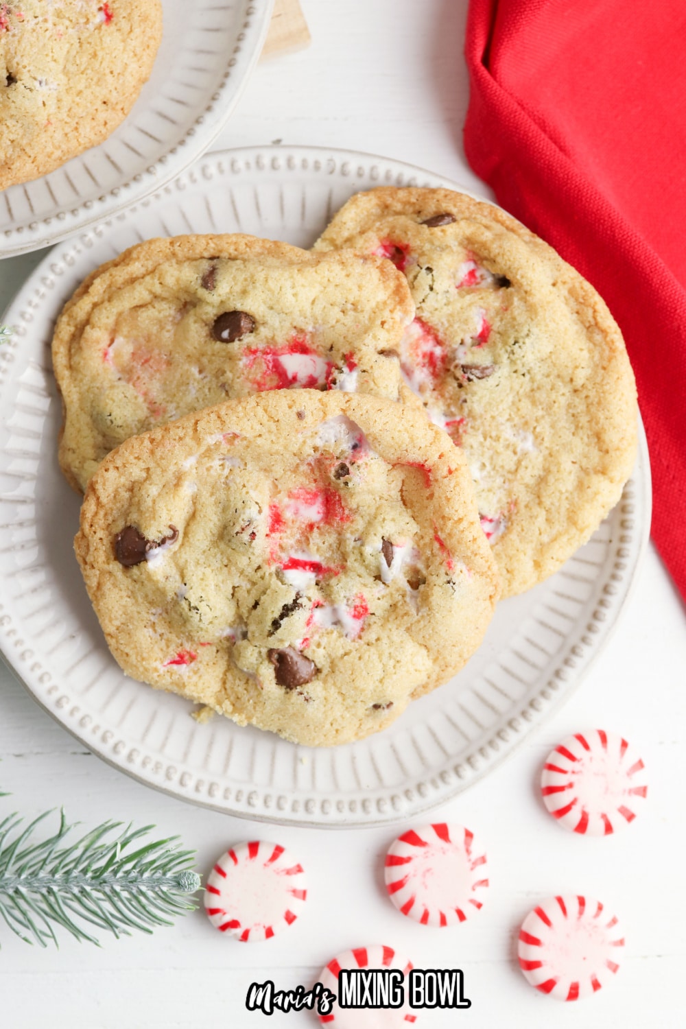 three peppermint chocolate chip cookies on a white plate with a few peppermint below it