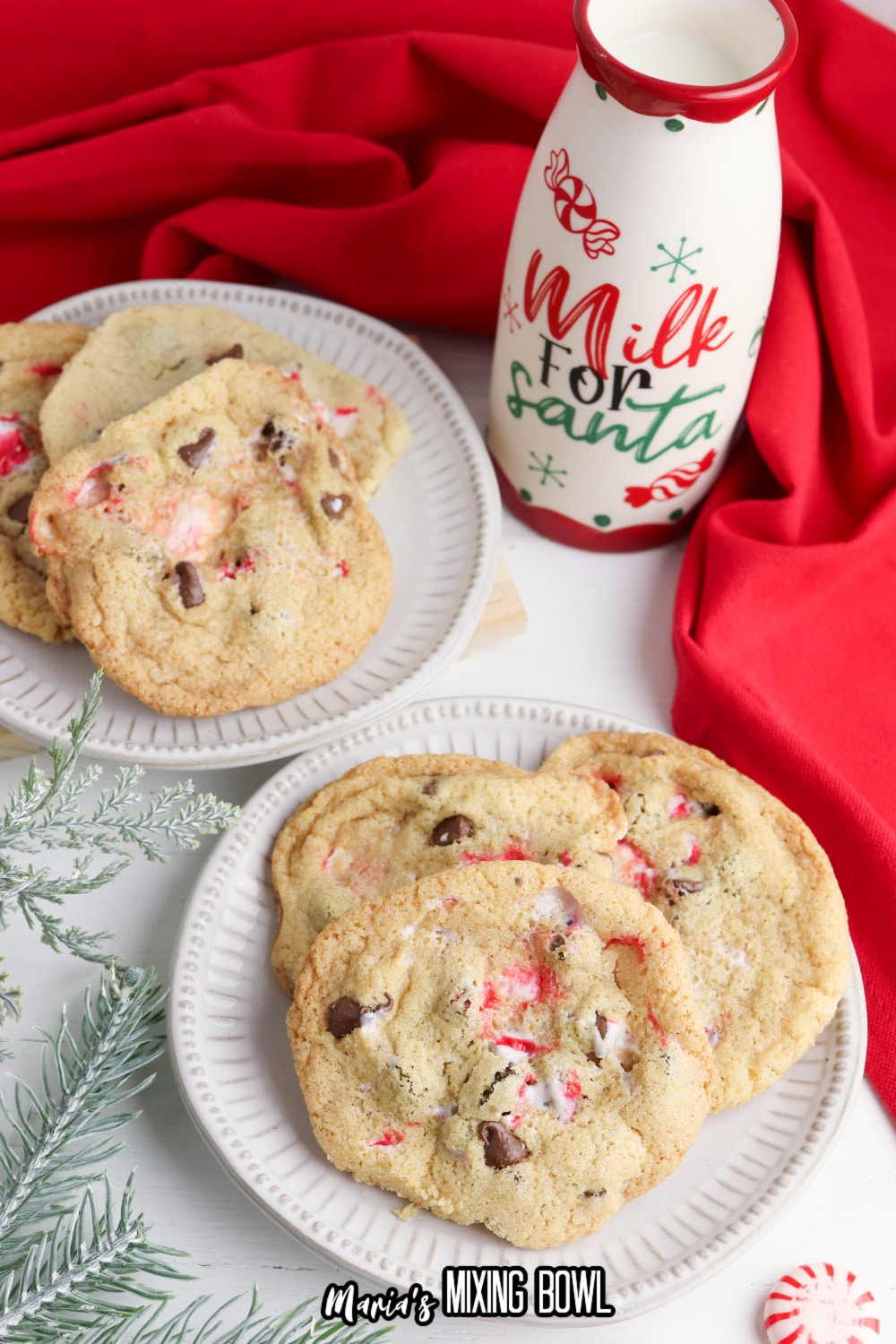 three cookies on a white plate with a milk for santa cup in the background
