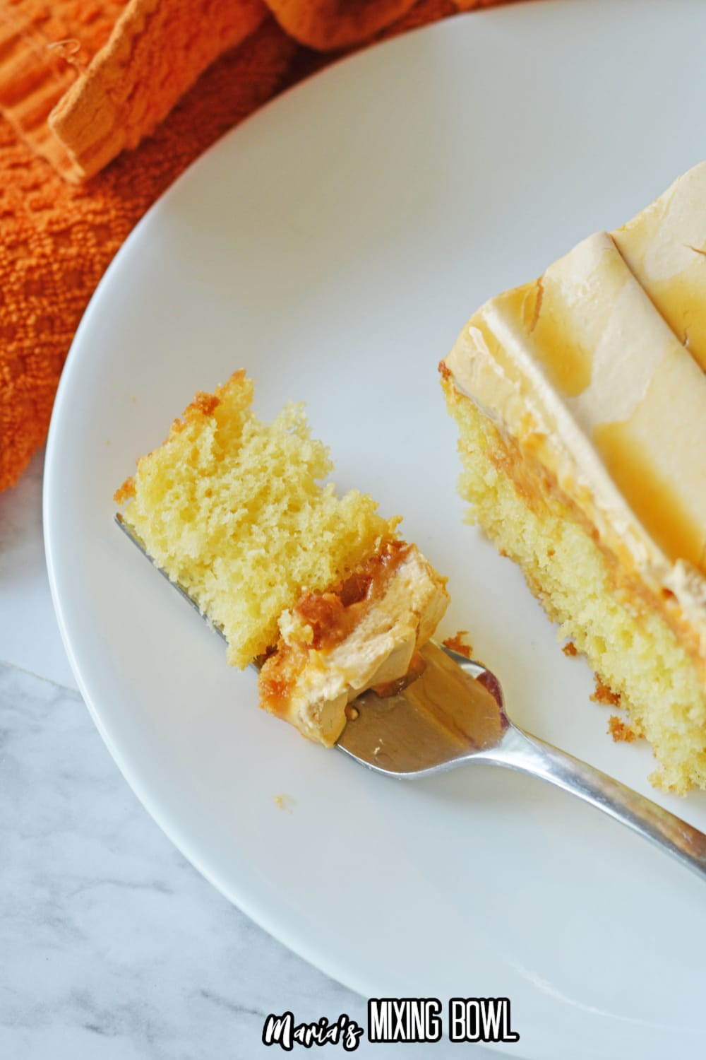Close up of a bite of cake on a silver fork on a white plate