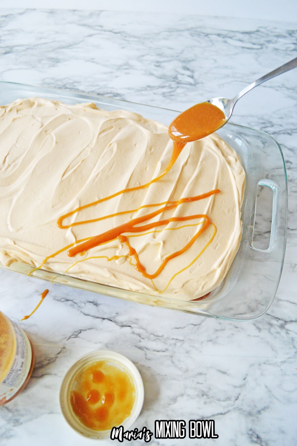 butterscotch sauce being drizzled over a frosted cake