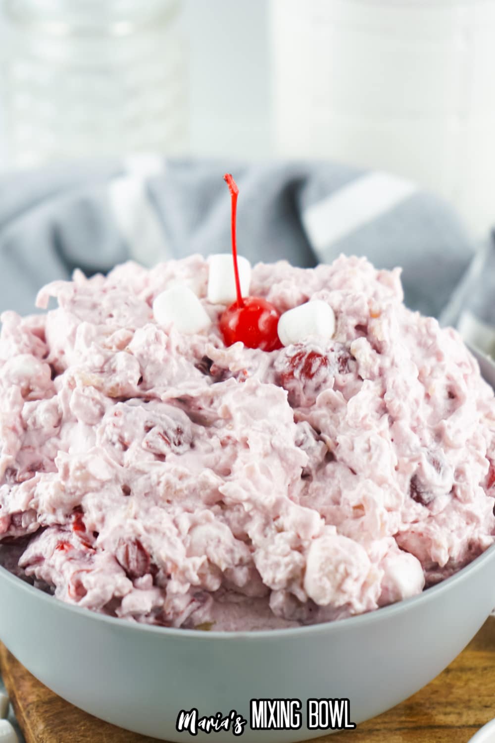 gray bowl filled with cherry fluff and topped with a cherry