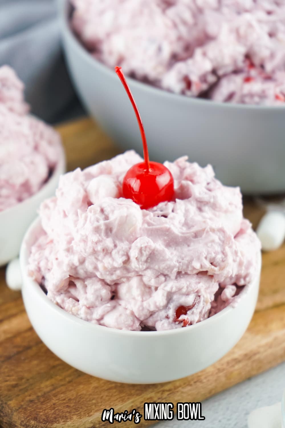 white bowl filled with cherry fluff and topped with a cherry