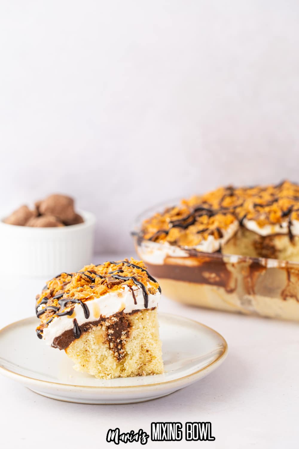 slice of chocolate butterfinger poke cake on a white plate