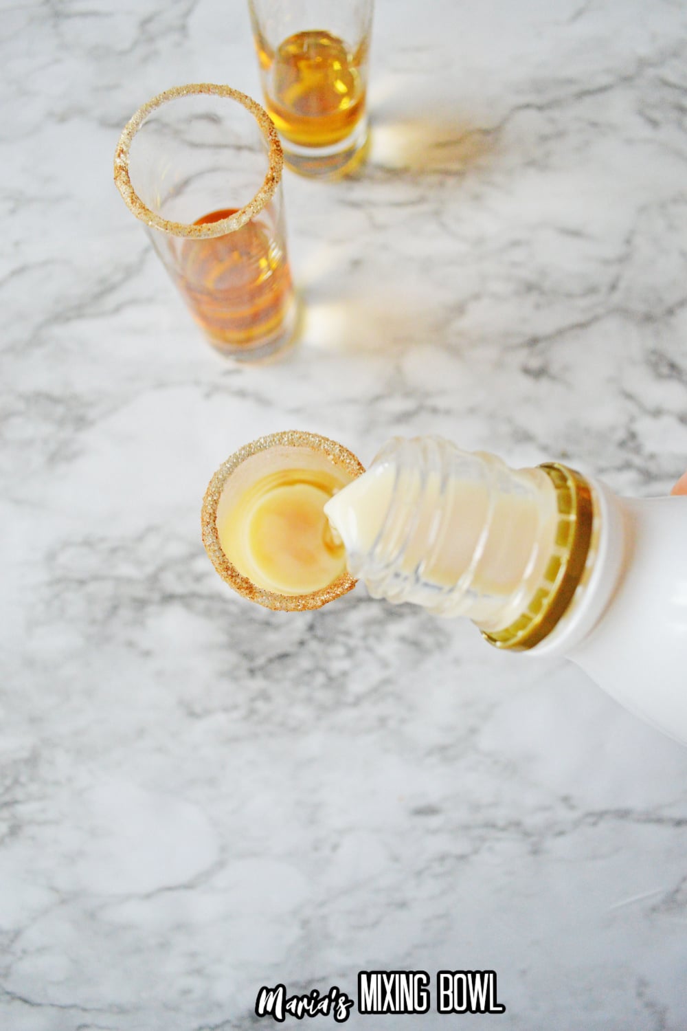 rumchata being poured into a cinnamon lined shot glass