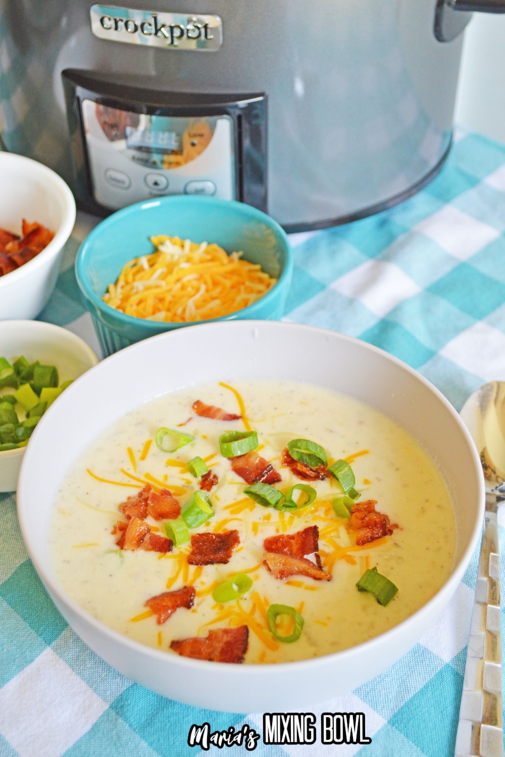 white bowl filled with crockpot loaded potato soup with bacon, green onions, and shredded cheese