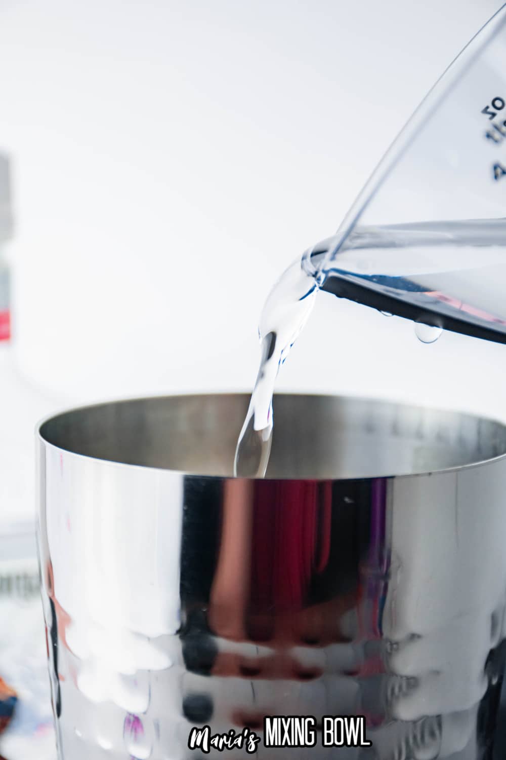 white rum being poured into a stainless steel cocktail shaker