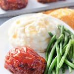 mini meatloaf, mashed potatoes, and green beans on a white plate