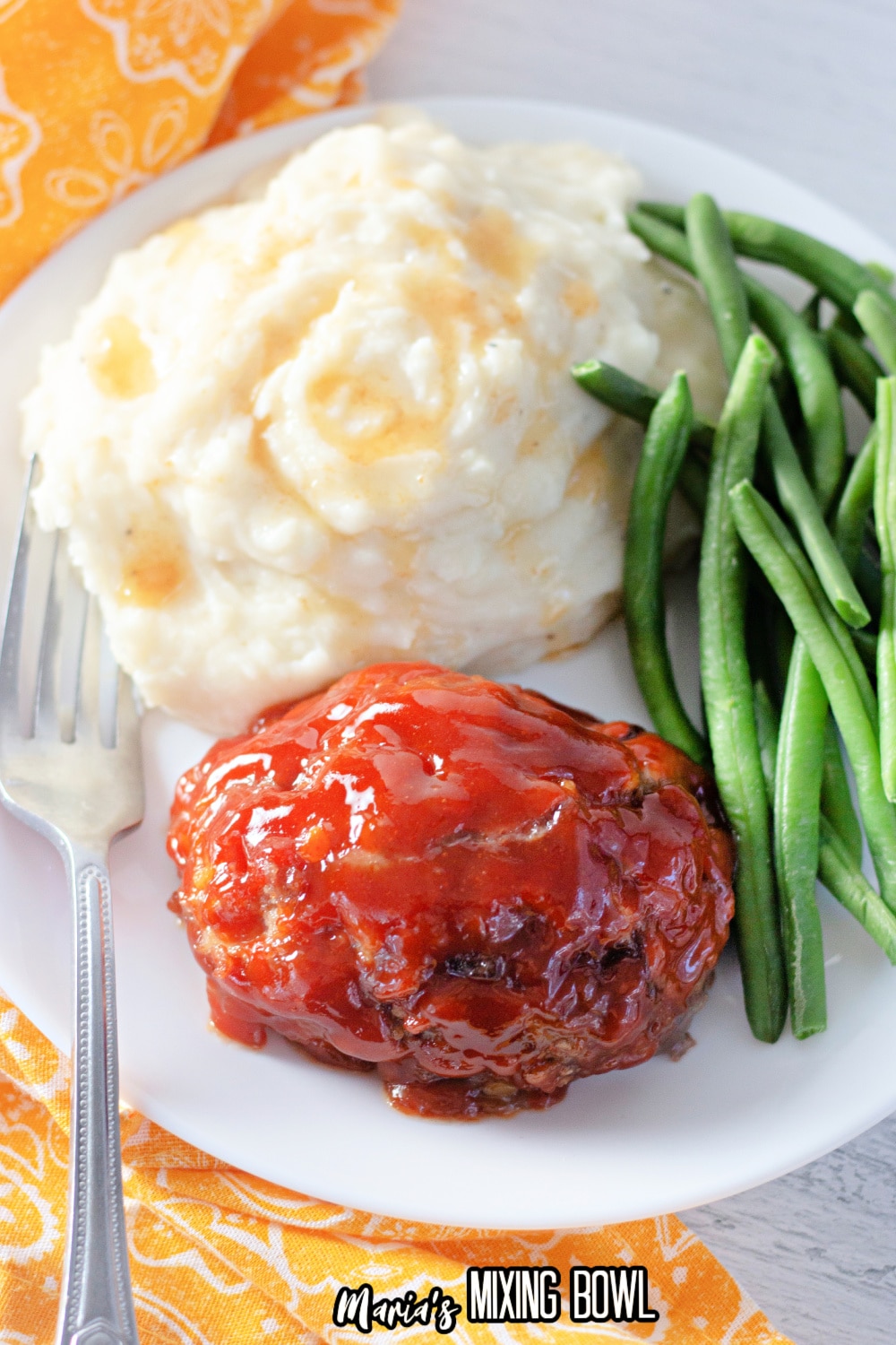 mini meatloaf, mashed potatoes and green beans on a white plate