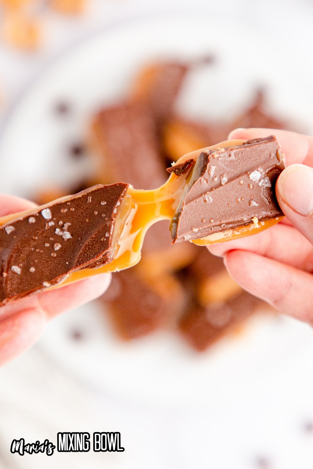 salted caramel chocolate bar being broke in a womans hands