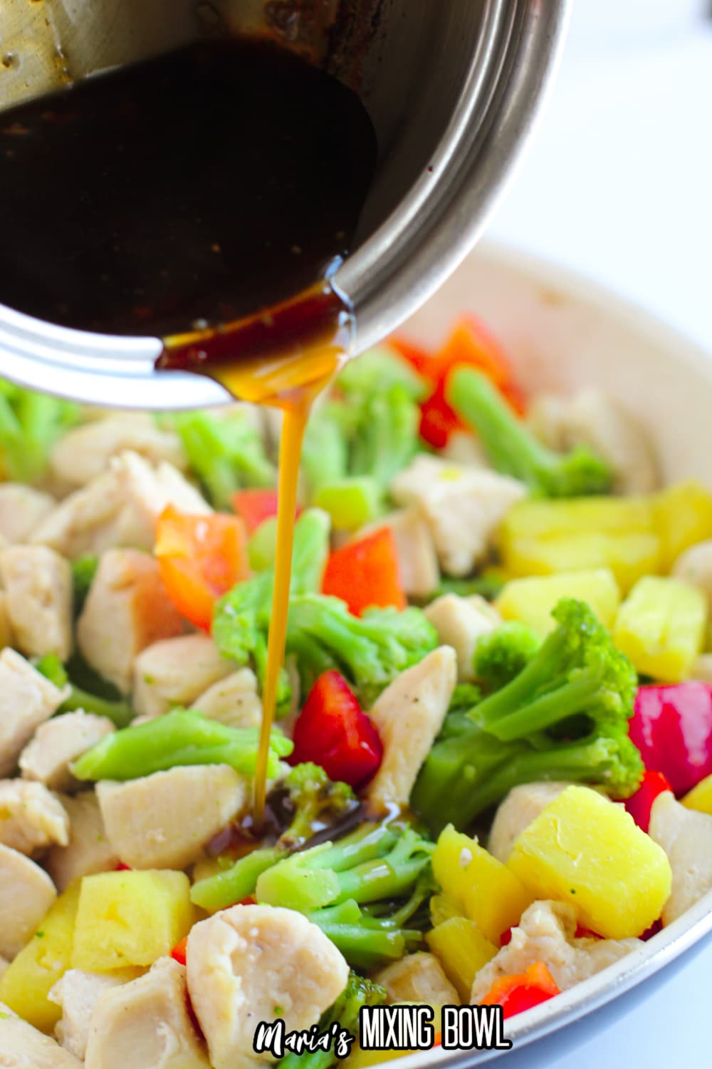 sauce being poured overed chicken and vegetables