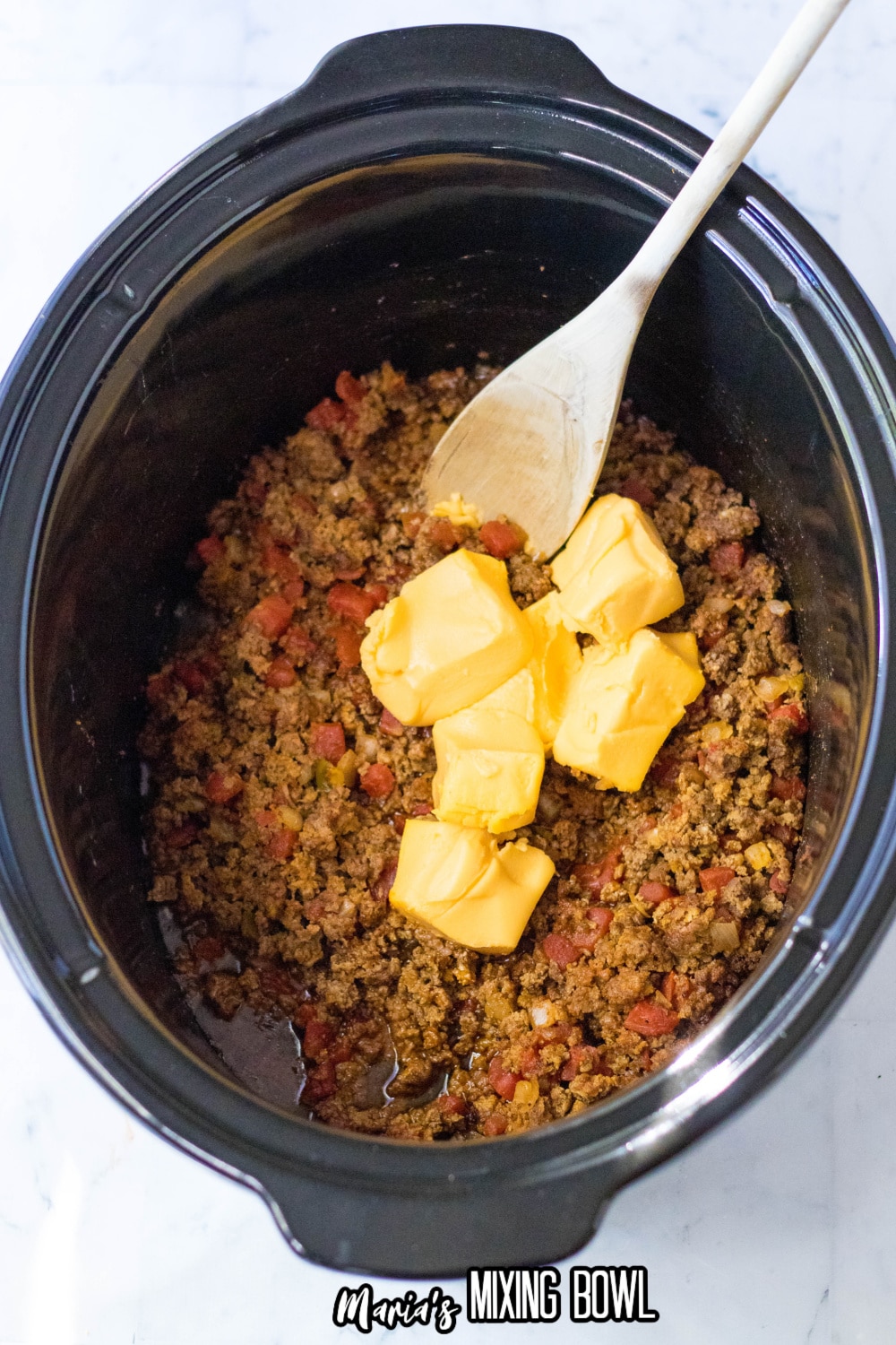 cubes of Velveeta cheese being added to the slow cooker