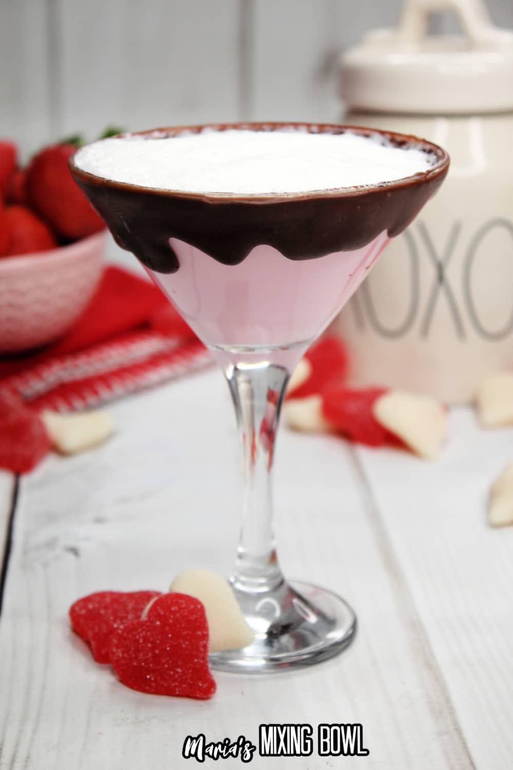 glass of strawberries and cream martini with a bowl of strawberries in the background