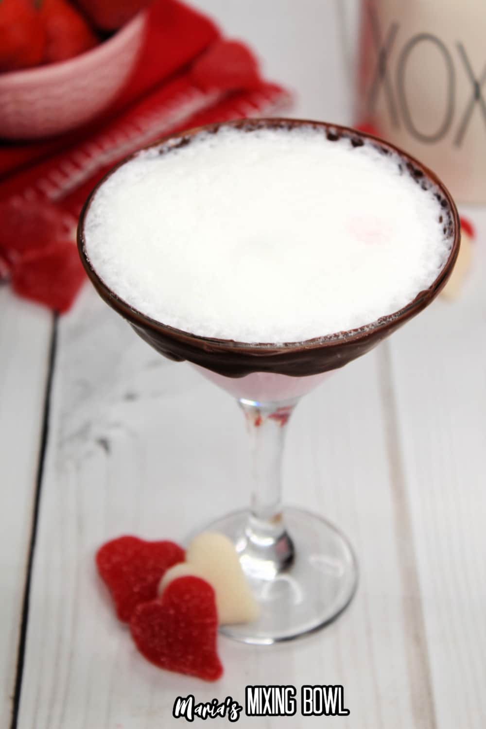 glass of strawberries and cream martini with a bowl of strawberries in the background