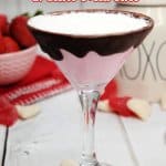 glass of strawberries and cream martini with a bowl of strawberries in the background