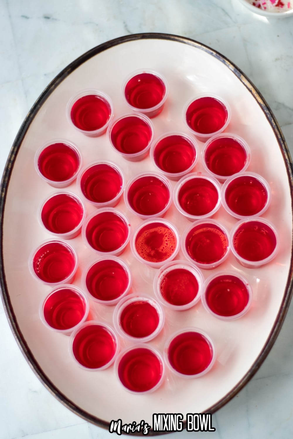 jello shots being filled on a white platter
