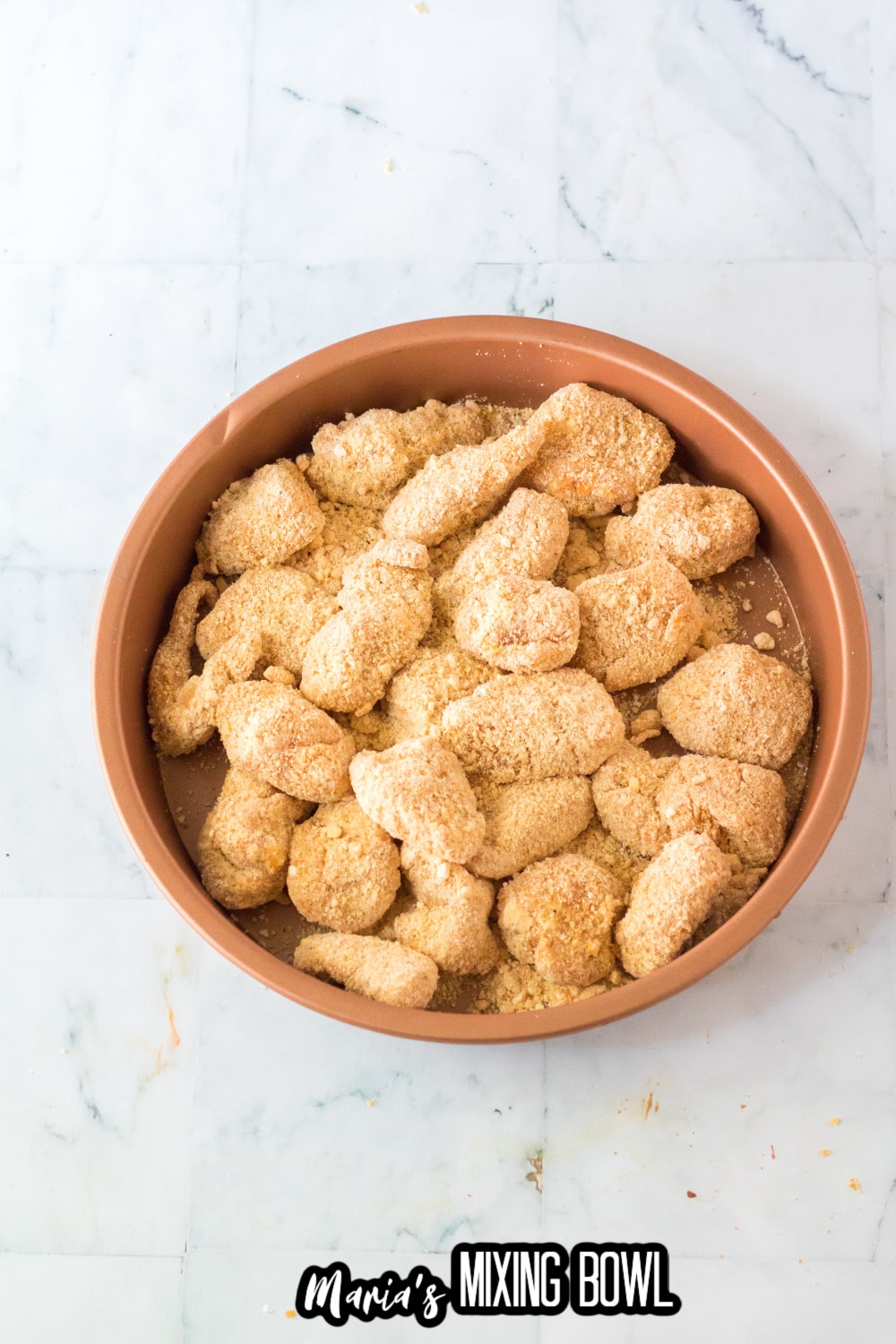 chicken nuggets breading in a baking dish