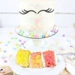 slice of bunny cake on a white plate with a full cake on a cake stand