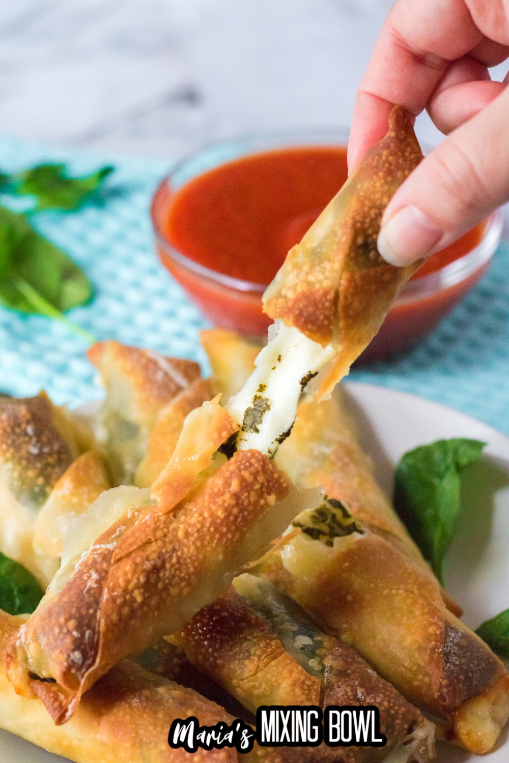 mozzarella stick broken in half and held in a woman's fingers