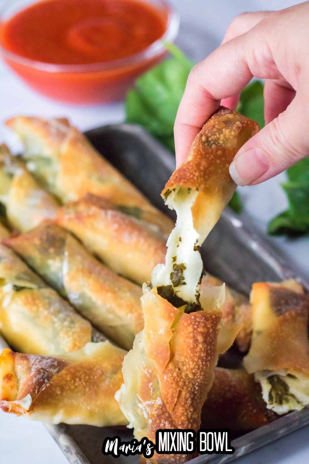 mozzarella stick broken in half and held in a woman's fingers