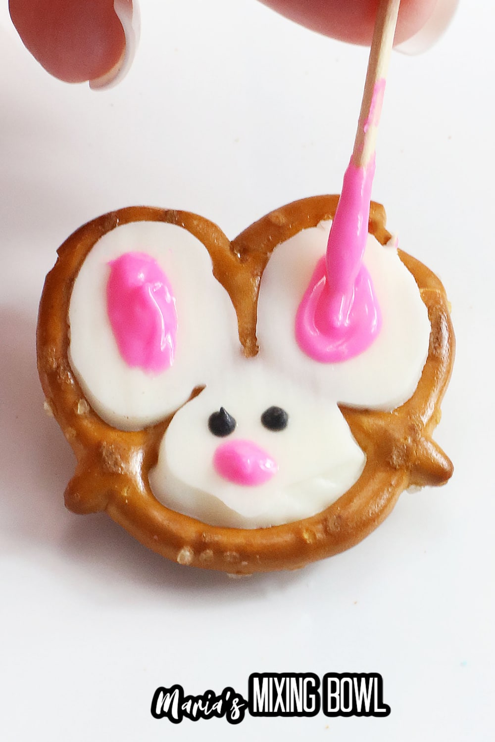 pink chocolate being adding to a pretzel