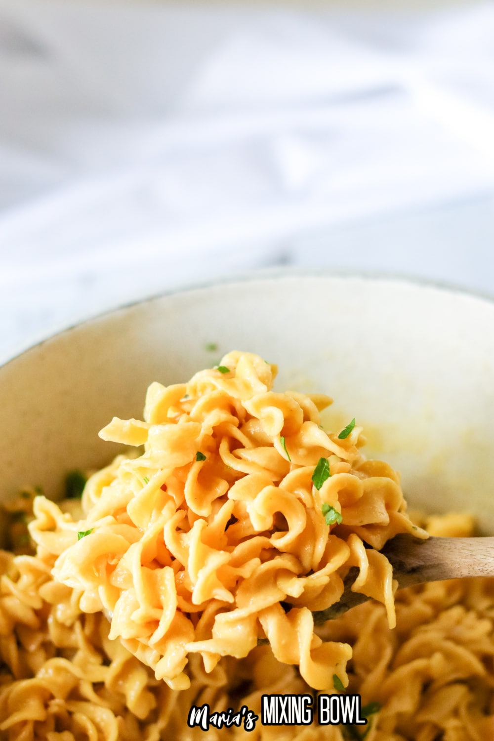 cafeteria noodles on a wooden spoon held above the pot