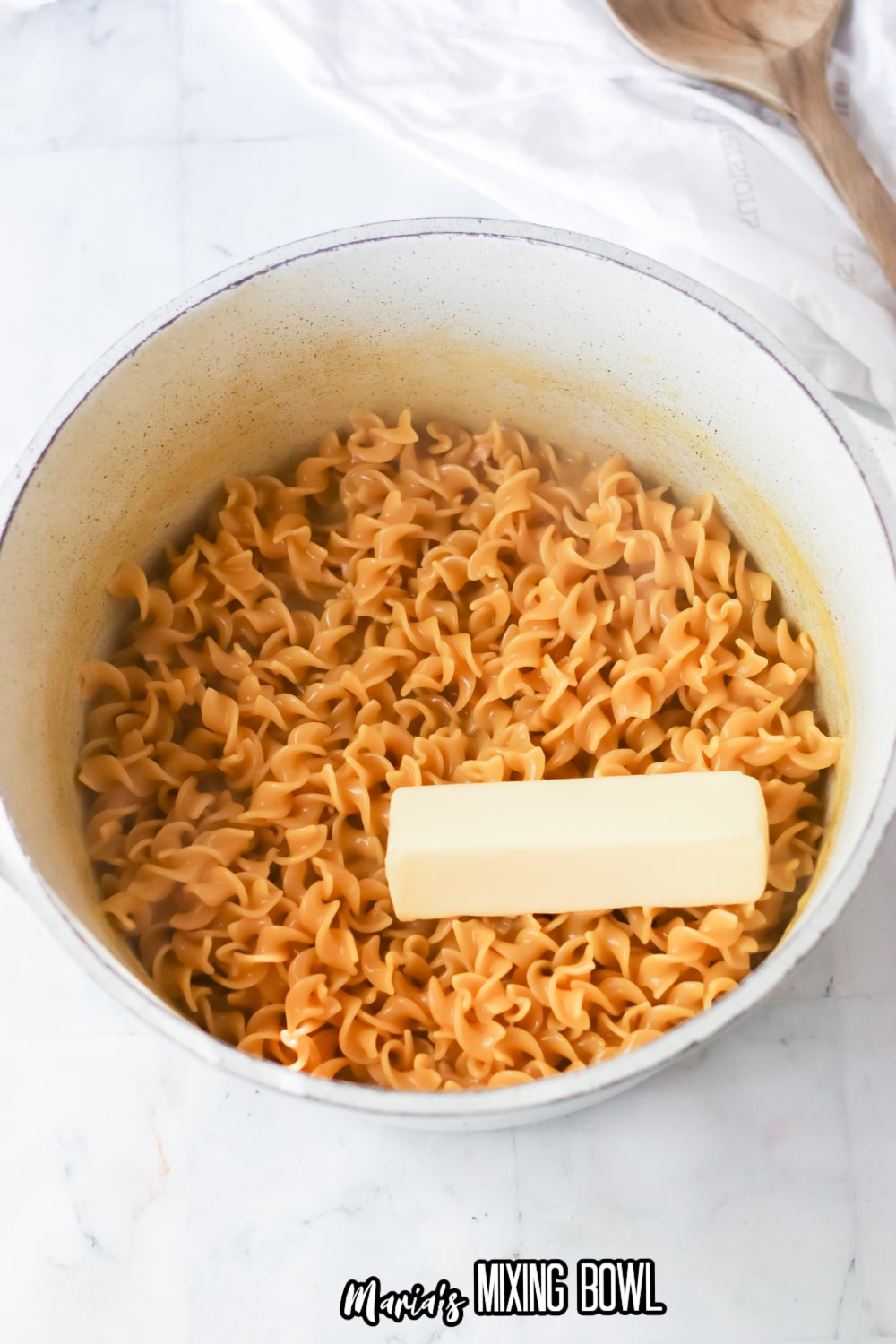 cooked egg noodles in a white pot topped with butter