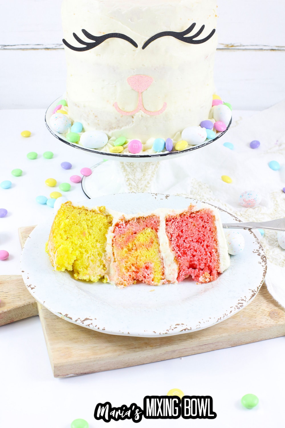 slice of bunny cake on a white plate with a full cake on a cake stand