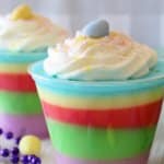 small plastic cups filled with colorful easter layered jello and topped with whipped cream