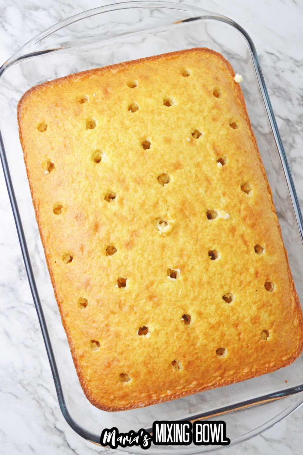 cake in a glass baking dish with holes being poked in it