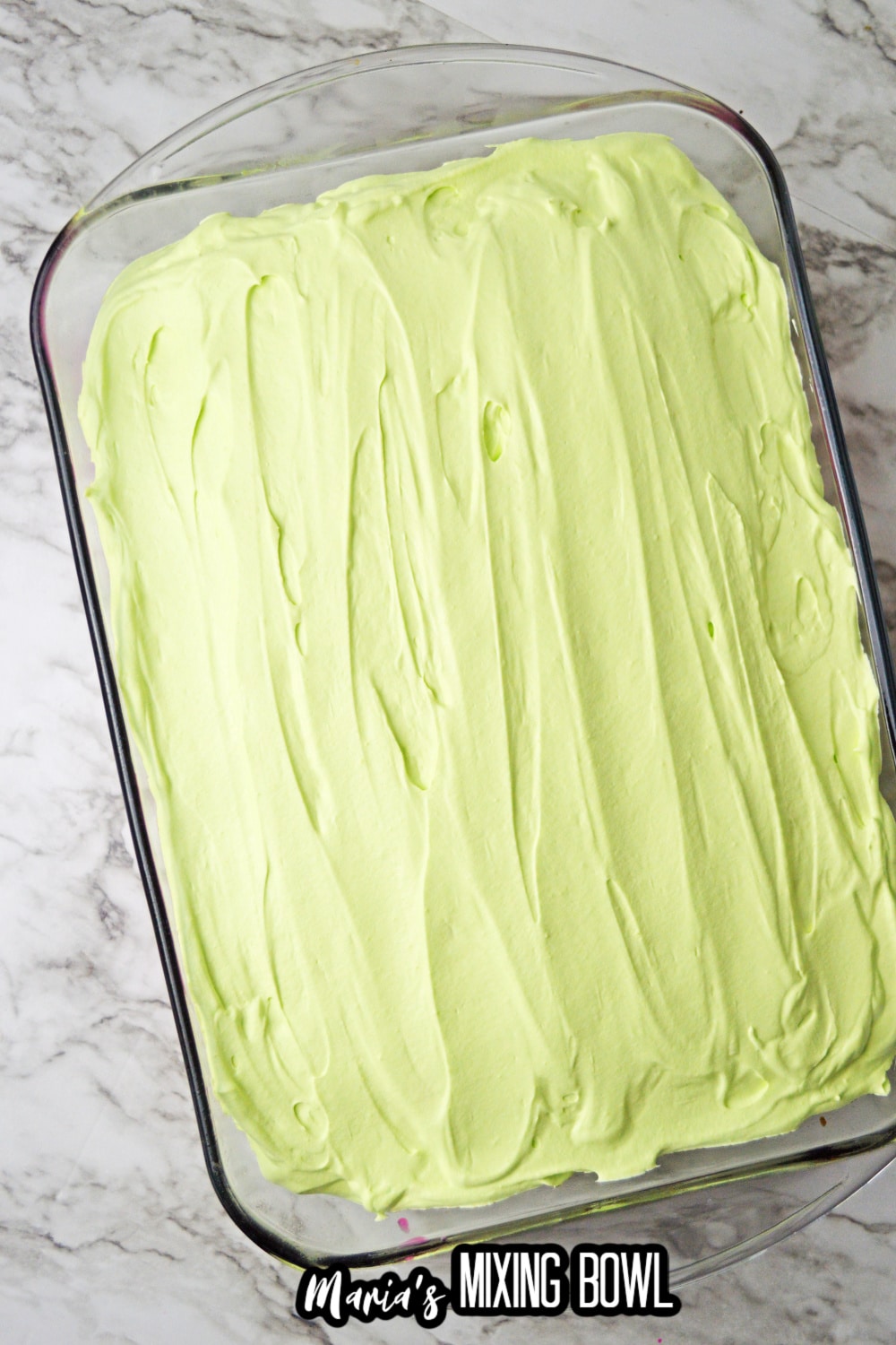 green frosting being spread on top of a finished cake