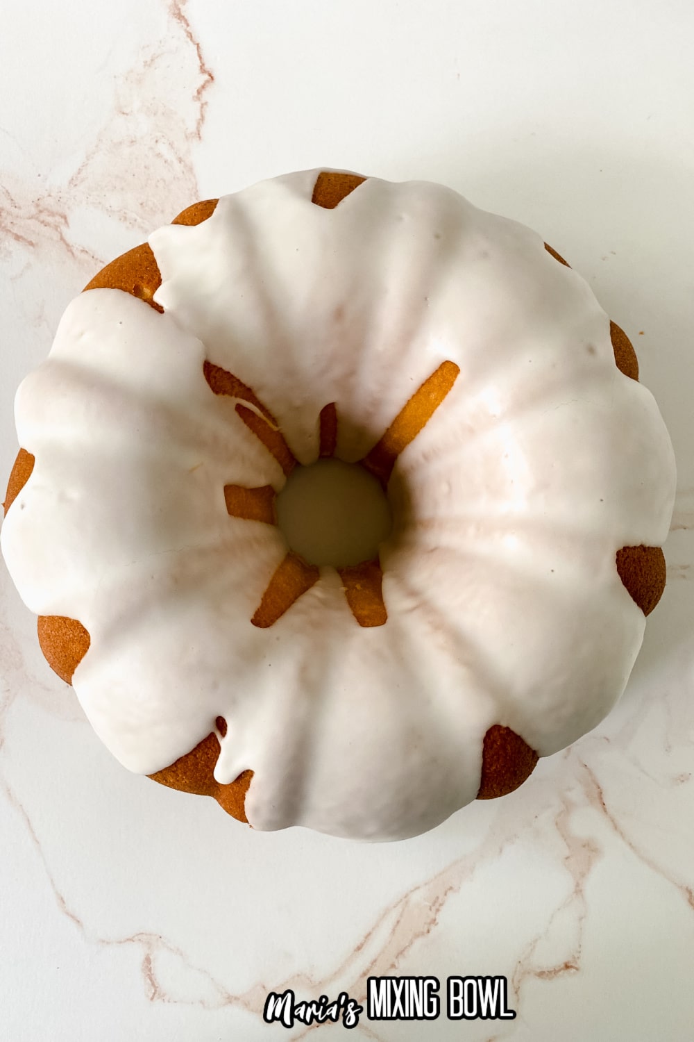 whole pound cake that has been glazed on a marble backdrop