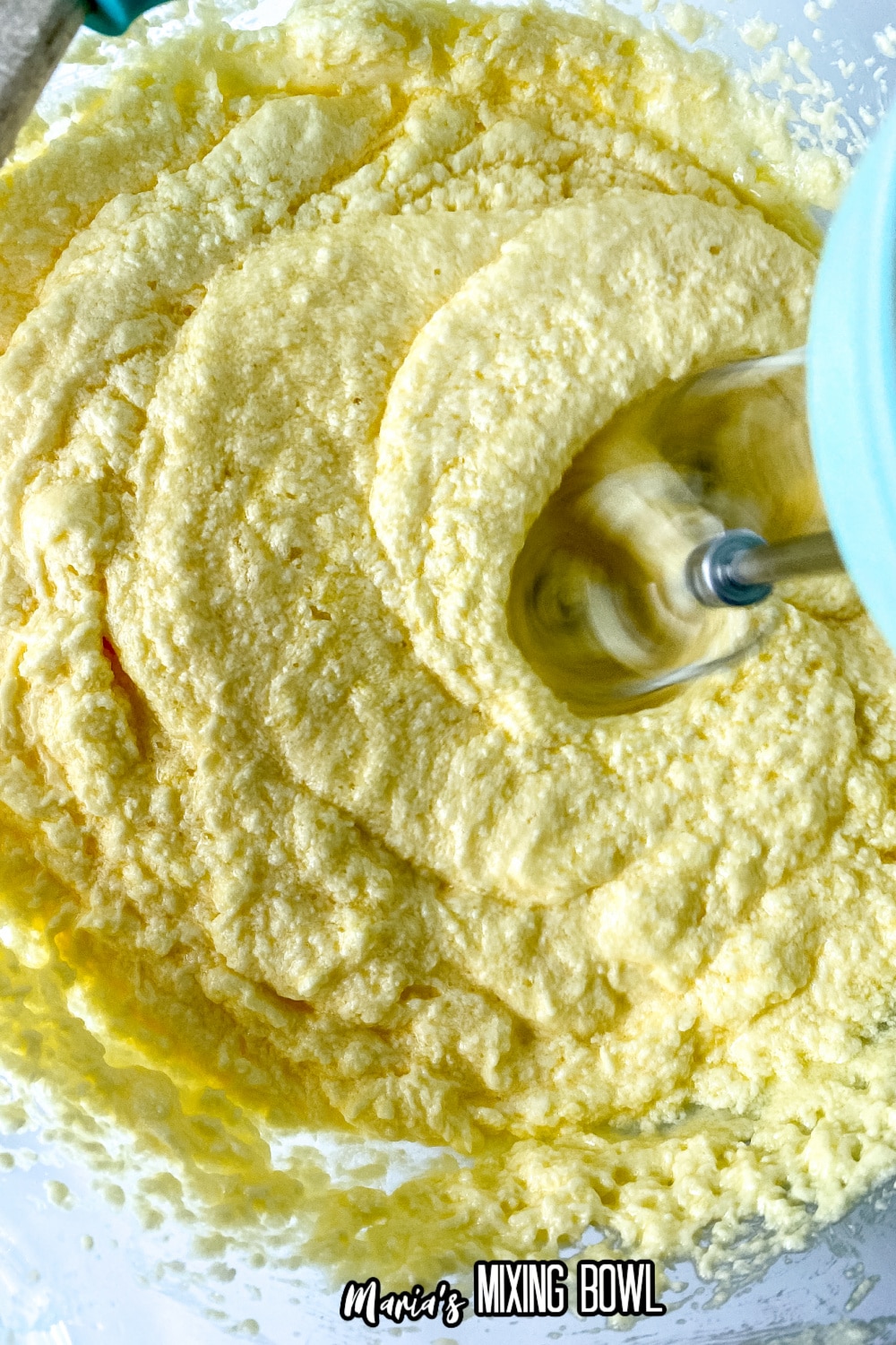 batter in a glass mixing bowl with a hand mixer doing the mixing