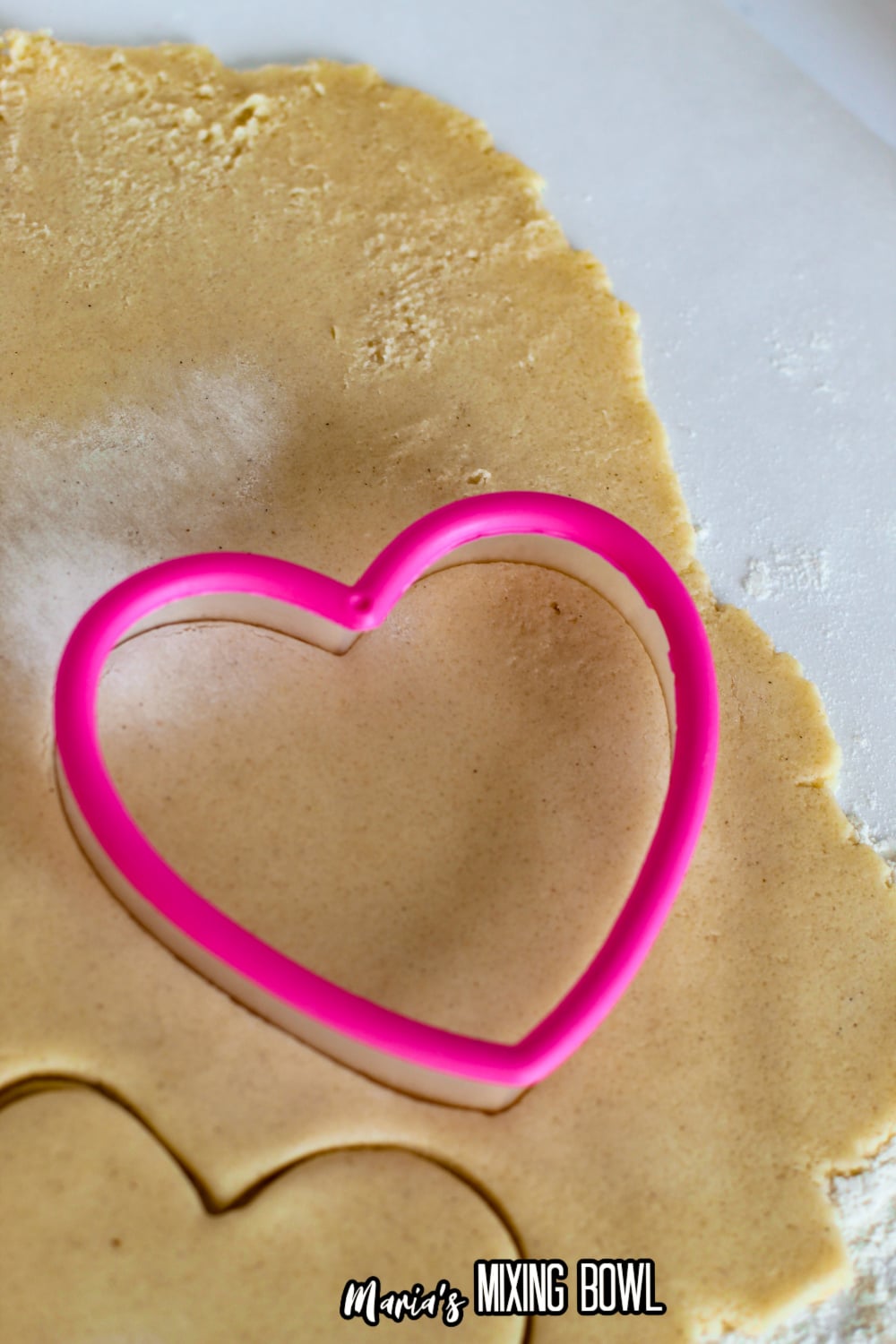 heart shaped cookie cutter cutting rolled out cookie dough