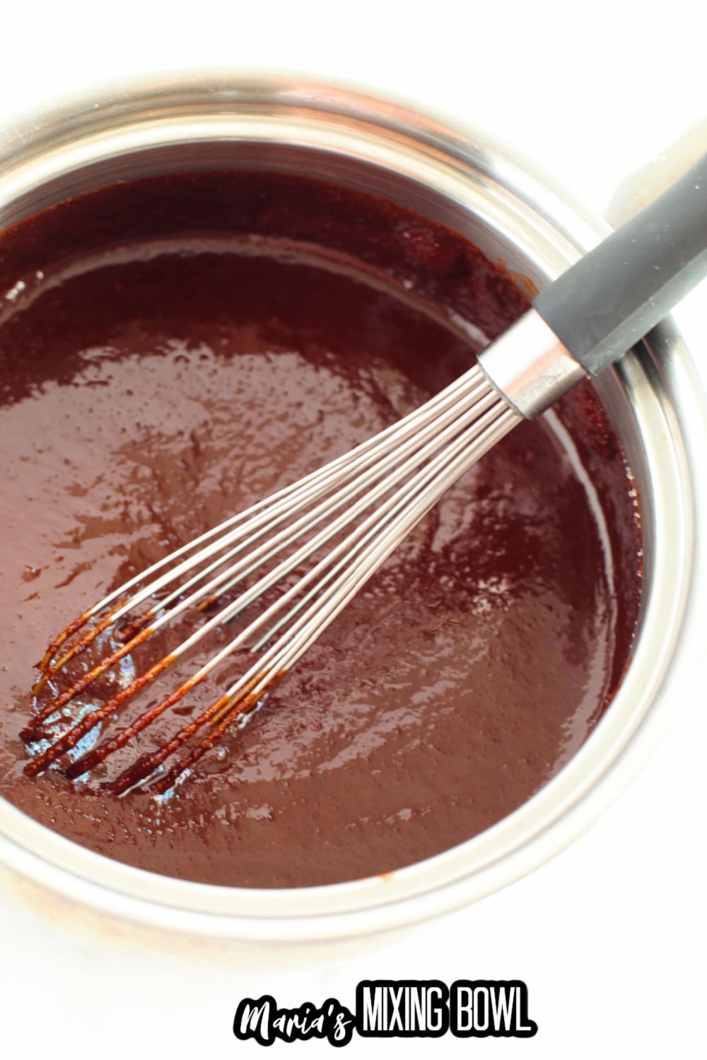 brownie batter in a stainless steel mixing bowl with a whisk
