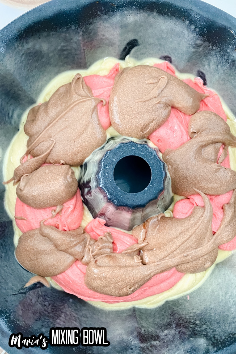 layers of vanilla, strawberry, and chocolate batter in a cake pan