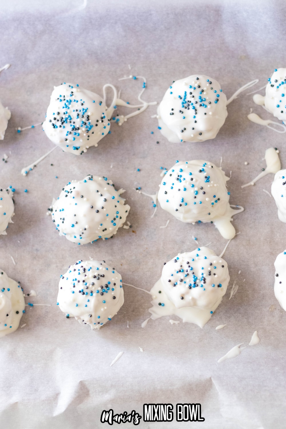 peanut butter balls with sprinkles being added on a parchment lined baking sheet