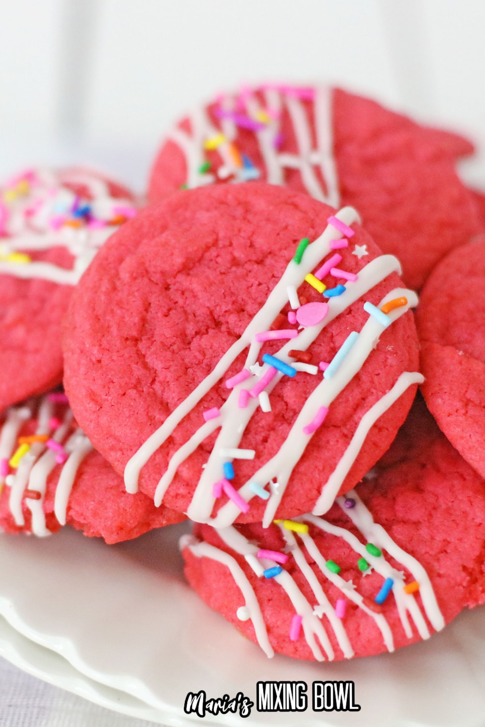 stack of decorated pink velvet cookies on a white plate