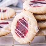 stack of raspberry cheesecake thumbprint cookies with one cookie on it's side leaning against the others