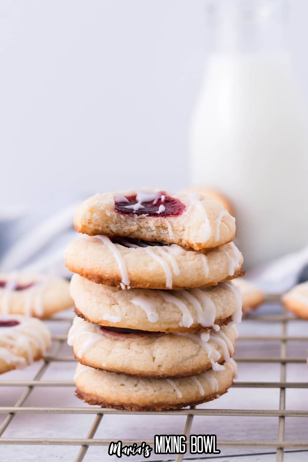 stack of raspberry cheesecake thumbprint cookies top one has bite missing