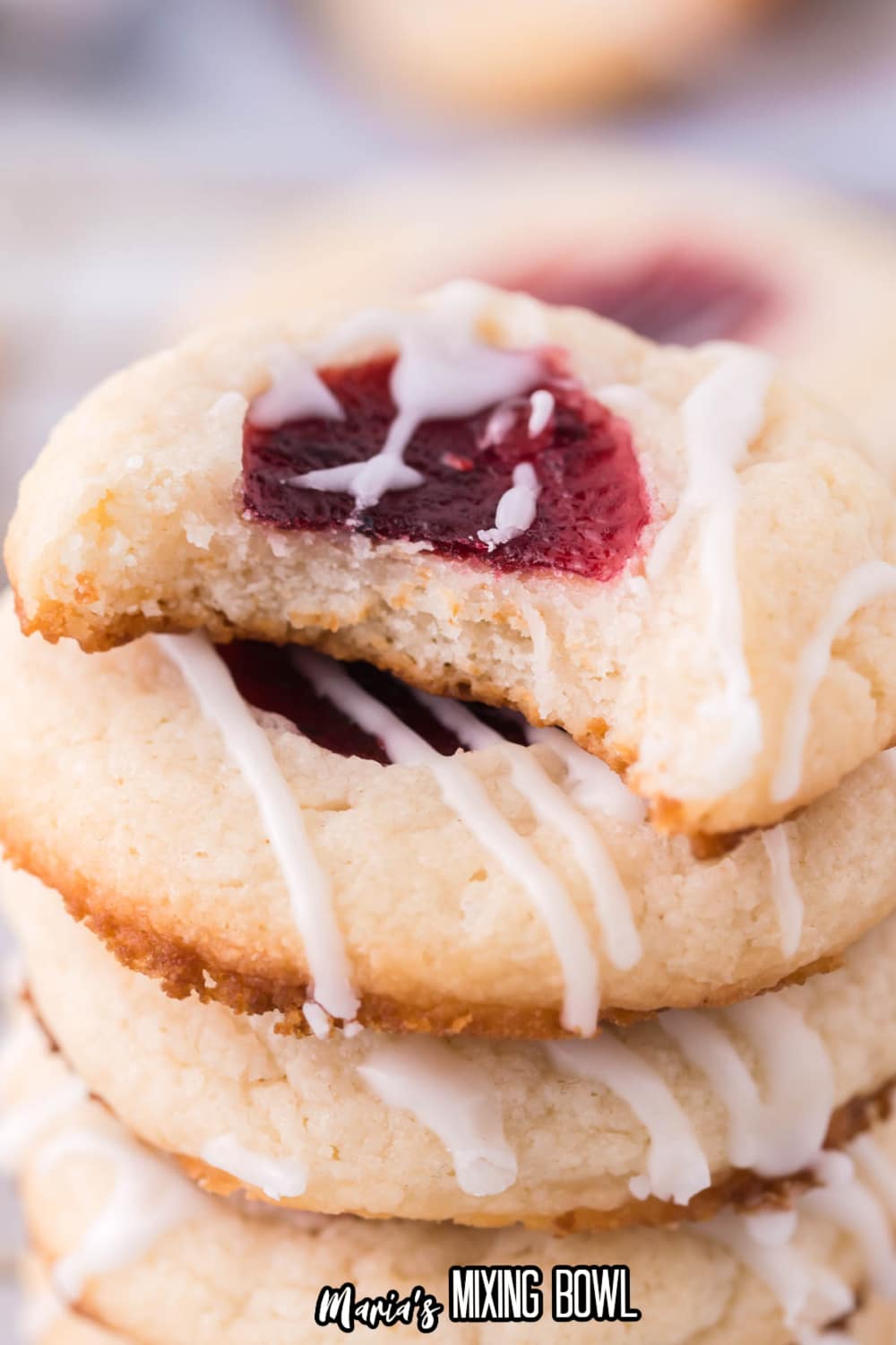 stack of raspberry cheesecake thumbprint cookies top one has bite missing