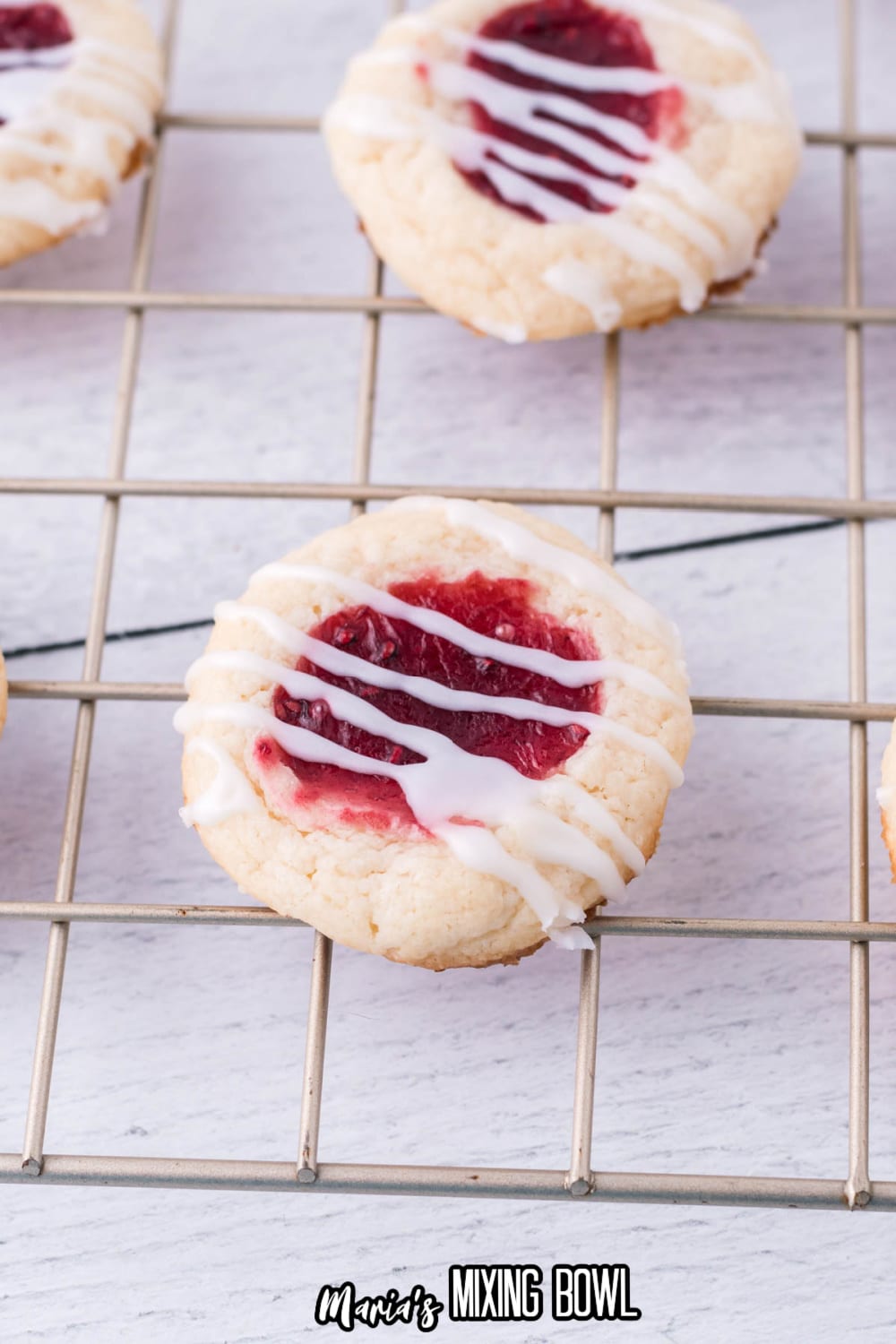 raspberry cheesecake thumbprint cookies on a wire cooling rack