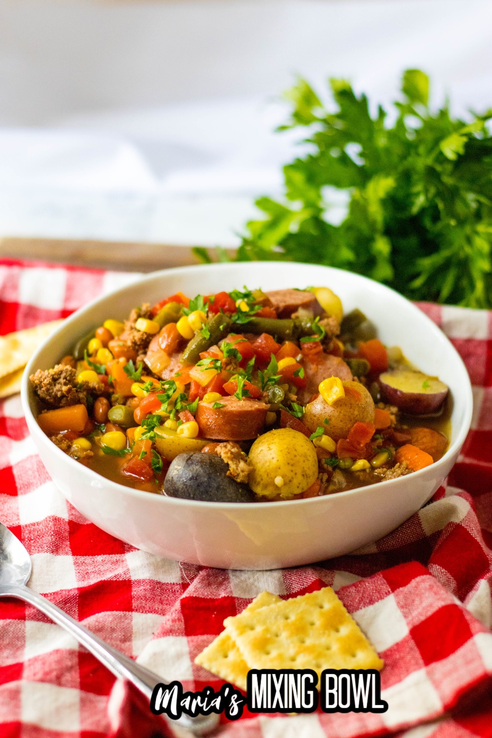 white bowl filled with slow cooker cowboy stew on a red and white napkin