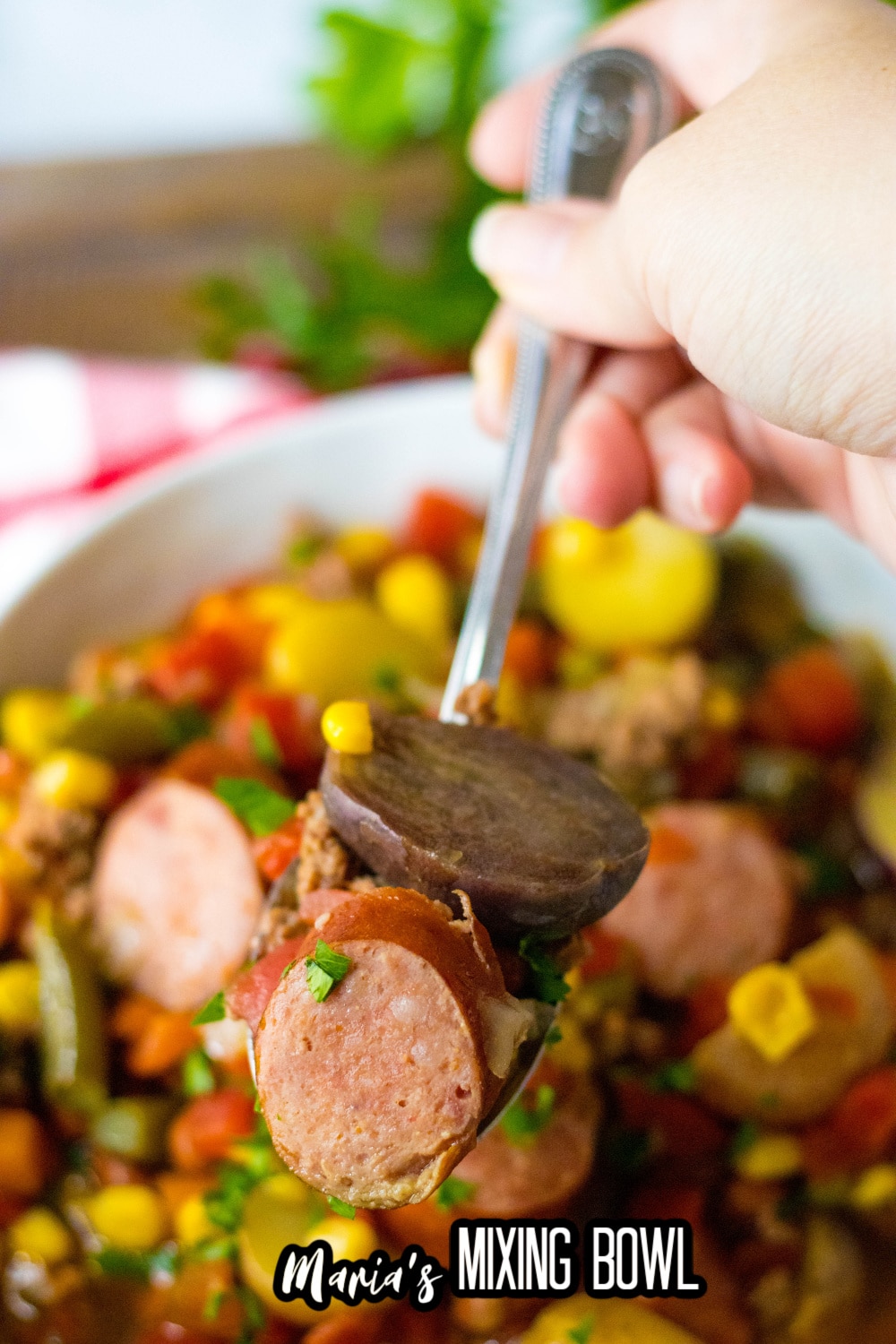 spoonful of smoked sausage and and potato held in the air